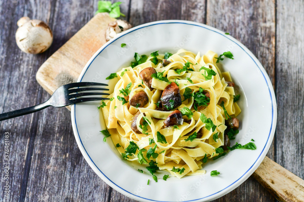 Italian food . Fresh home made  tagliatelle vegetarian  egg pasta  with mushrooms ,parmesan cheese ,fresh parsley  and black pepper.