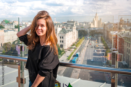 A young woman smiling on the roof with a panorama of Moscow