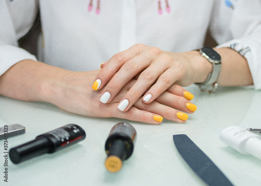 beautiful manicure in yellow and white color and a set for manicure, close-up