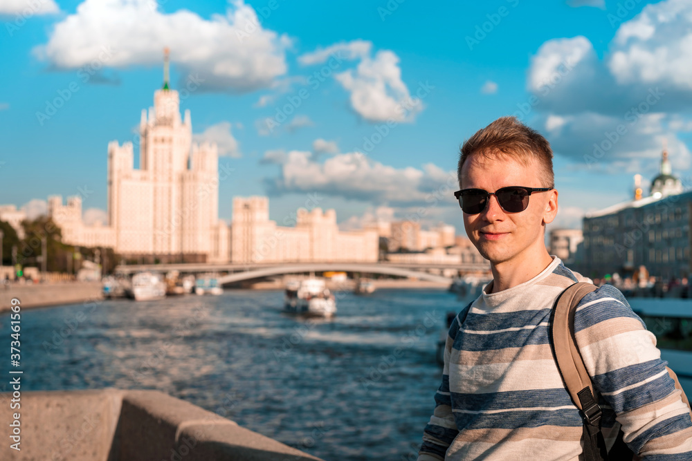 Portrait of a young blond man with the background of the famous high-rise building and the Moscow river on a Sunny summer day