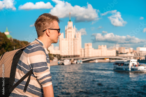 Portrait of a young blond man with the background of the famous high-rise building and the Moscow river on a Sunny summer day © KseniaJoyg