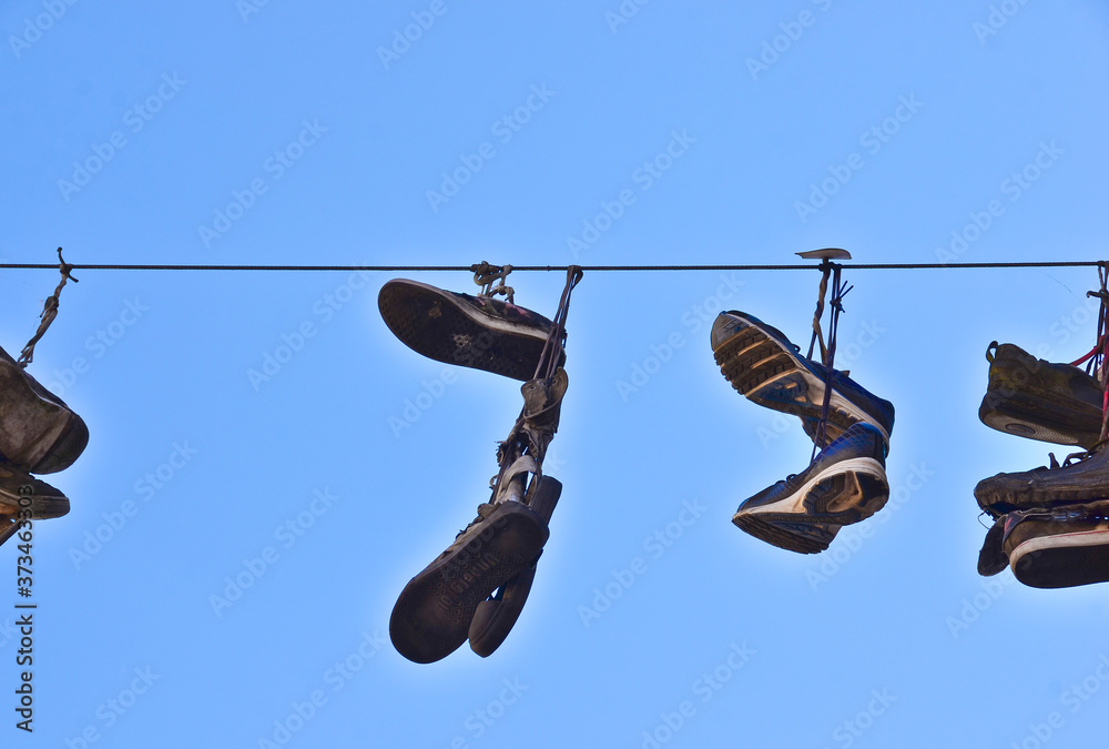 Many old shoes hanging on a string between two houses, a practice of students, who finished their studies in Flensburg / Germany Many old shoes hanging on a string between two houses, a practice of students, who finished their studies in Flensburg / Germany