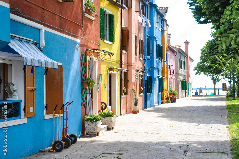 View of a narrow street in Burano in Italy. Beautiful colorful houses in sunny weather. - obrazy, fototapety, plakaty 