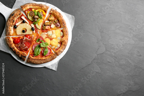 Slices of different pizzas on grey table, top view. Space for text