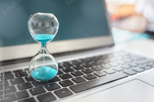 Hourglass on laptop computer concept for time management photo