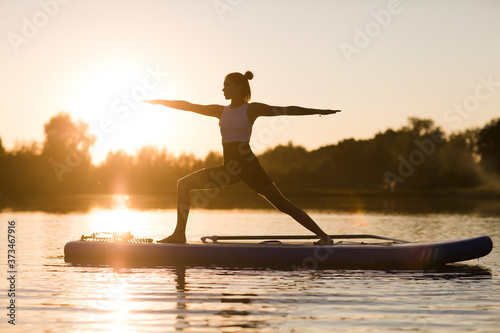 woman doing yoga on sup board at sunset. outdoor summer activity. Sup yoga.  Social Distancing. copy space. Mental Health photo