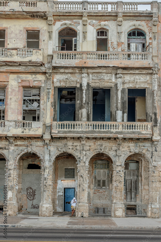 old facade, with boy leaning on the column in Havana