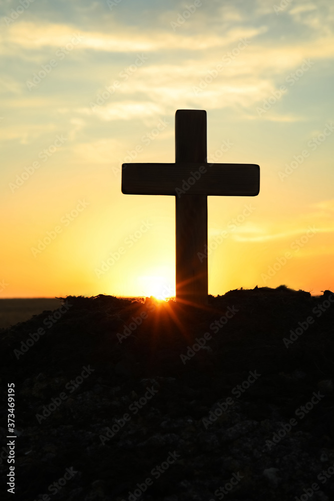 Silhouette of Christian cross outdoors at sunrise. Religion concept