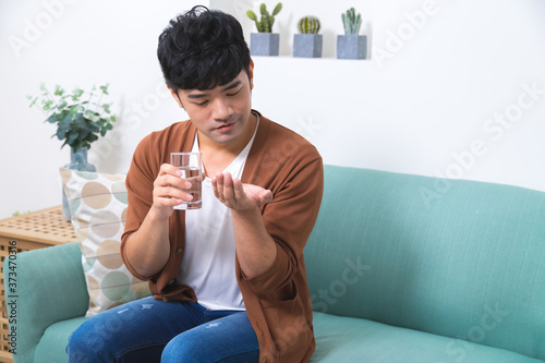 Asian man taking medicines at home.