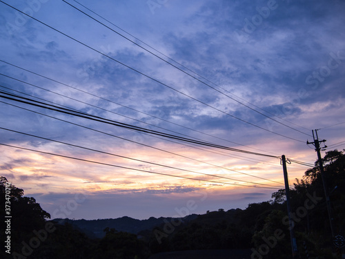 purple sky with cloud before sunset and silhouette of electric pole with cable lines