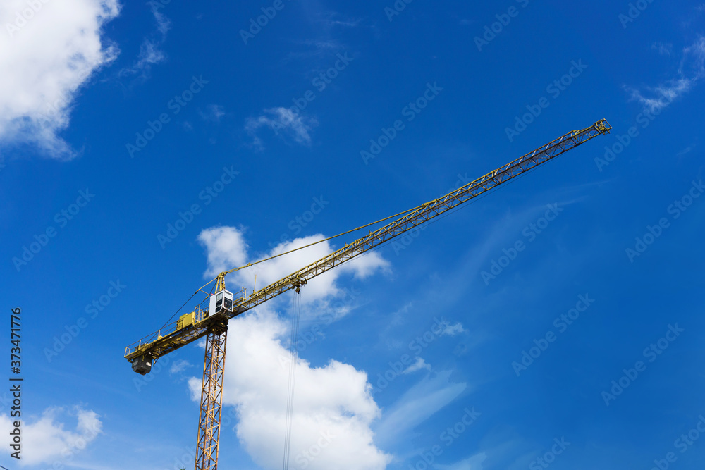 Empty copy space crane background. Yellow paint heavy machinery equipment isolated on blue cloudy sky. Construction site view. Industrial building process. Empty copy space crane background. Yellow paint heavy machinery equipment isolated on blue cloudy sky. Construction site view. Industrial building process.