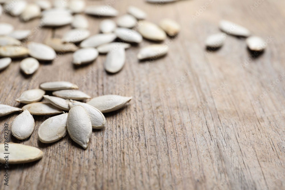 Closeup view of raw pumpkin seeds on wooden background, space for text. Vegetable planting