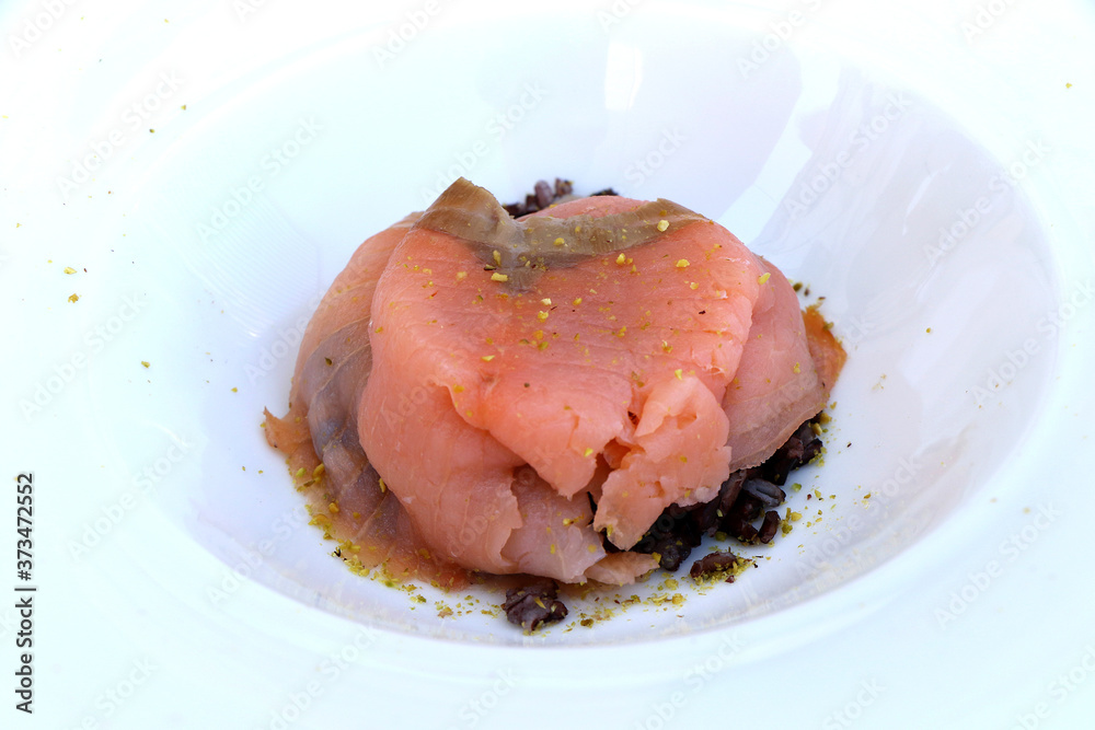 Slices of smoked salmon with chopped pistachios over black rice Slices of smoked salmon with chopped pistachios over black rice