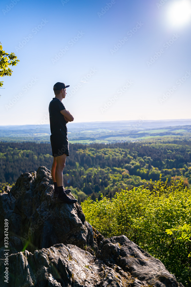 Obraz premium Trail runner stands on a rock in the mountains