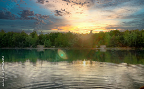 Dramatic sunset over a body of water surrounded by trees. High quality photo