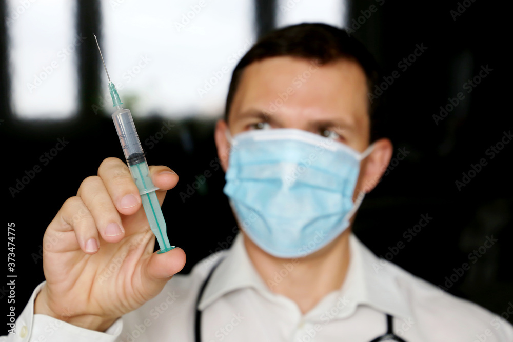 Doctor with syringe, man in medical mask preparing to injection. Concept of vaccination during covid-19 pandemic Doctor with syringe, man in medical mask preparing to injection. Concept of vaccination during covid-19 pandemic