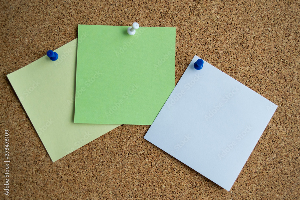 Three paper notes green, white and yellow color on a cork Board, attached with a white pushpin. Copy space Three paper notes green, white and yellow color on a cork Board, attached with a white pushpin. Copy space