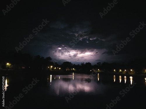 Lighting between the cumulonimbus clouds reflection on a lake