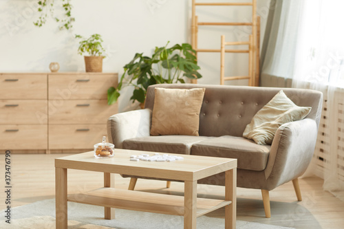 Warm toned background image of cozy home interior featuring comfortable beige sofa and coffee table, copy space