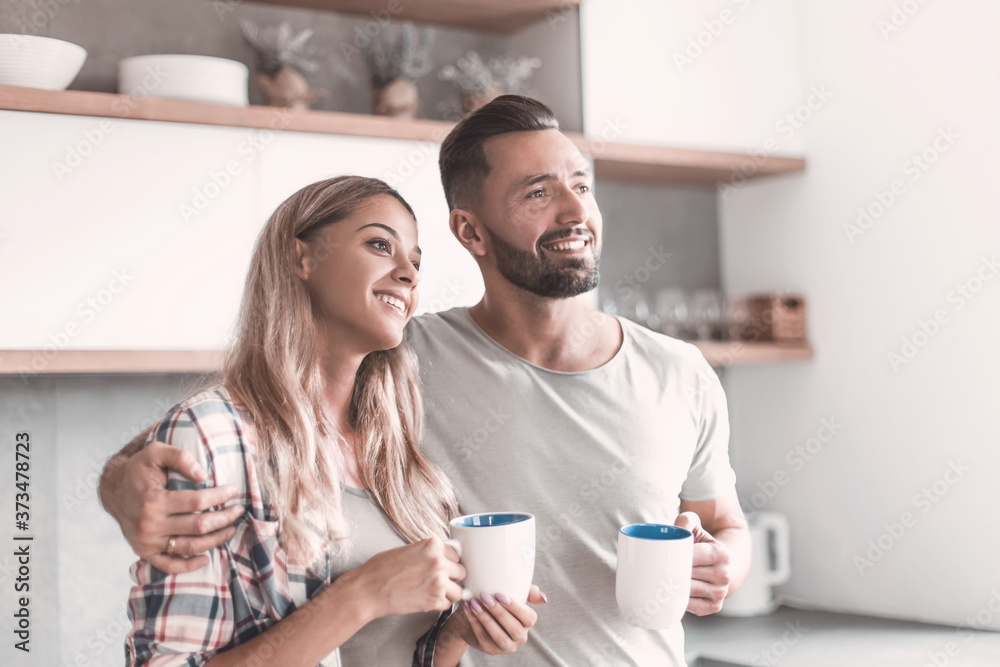 young couple drinking coffee standing in the kitchen