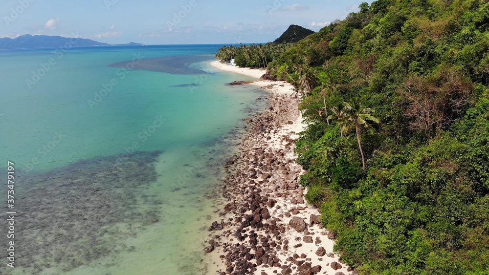 Green jungle and stony beach near sea. Tropical rainforest and rocks near calm blue sea on white sandy shore of Koh Samui paradise island, Thailand. Dream beach drone view. Relax and holiday concept.