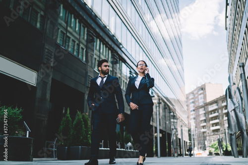 Canvas Print Serious businesswoman and partner walking in downtown street speaking on smartph