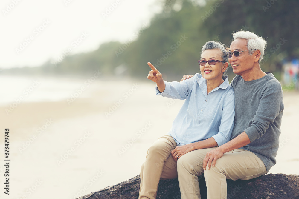 Asian Lifestyle senior couple hug and pointing on the beach happy in love romantic and relax time.  People tourism elderly family travel leisure and activity after retirement in vacations and summer