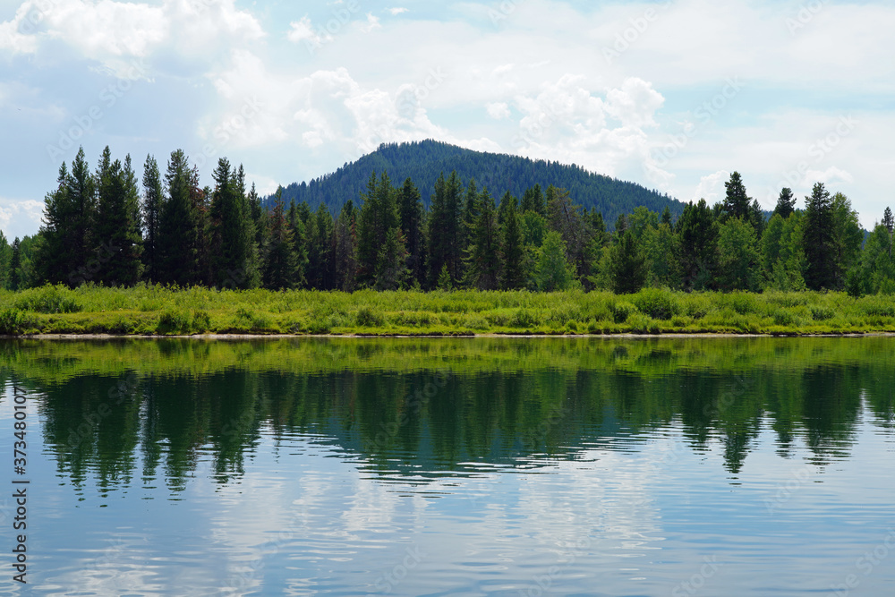 View of mountain peaks reflecting in water in summer in Grand Teton National Park in Wyoming, United States