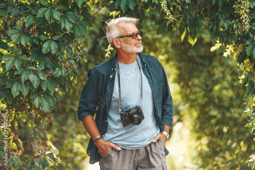 Принти на полотні A mature man with a beard walks in the park with a camera
