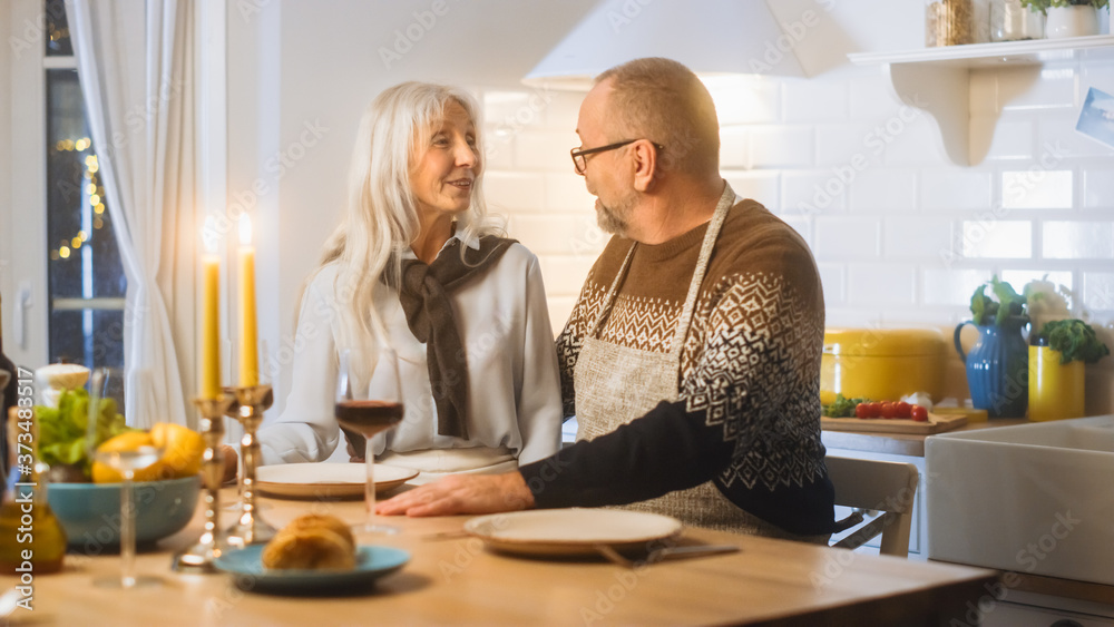 Happy Senior Couple in Love Have Romantic Evening, Cooking and Having Dinner in the Kitchen, Celebrating Anniversary. Elderly Have Romantic Evening with Wine, Festive Table in Cozy Kitchen Interior Happy Senior Couple in Love Have Romantic Evening, Cooking and Having Dinner in the Kitchen, Celebrating Anniversary. Elderly Have Romantic Evening with Wine, Festive Table in Cozy Kitchen Interior