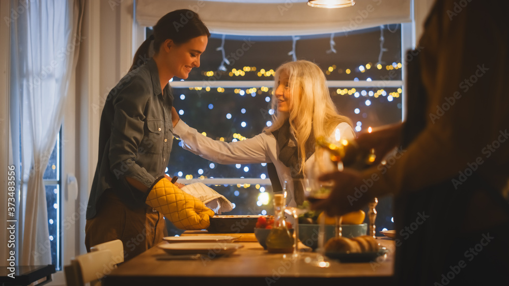 Young Mother Takes Casserole Dish out of Oven and Puts it on a Table. Happy Family Celebrating together, Gathering around Table with Delicious Dinner Meal. Young Mother Takes Casserole Dish out of Oven and Puts it on a Table. Happy Family Celebrating together, Gathering around Table with Delicious Dinner Meal.