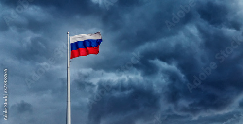Russia flag waving on blue storm hurricane clouds sky background © Parilov