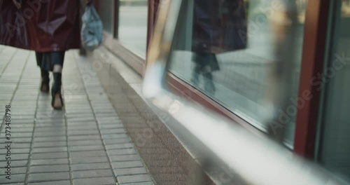 Unrecognized lady wearing high heels holds a mask of a rabbit, she stands near a window and watches her reflection, then goes away