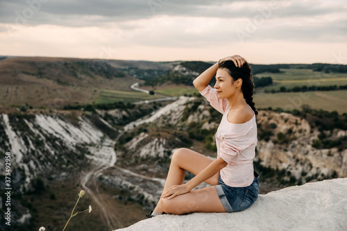 Young woman sitting on a top of a hill watching landscapes.