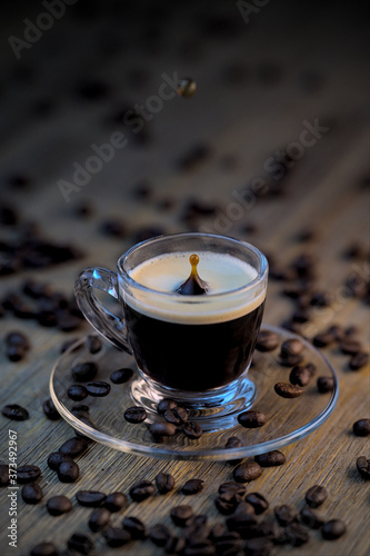 Drop falling into a cup of coffee. On a wooden background