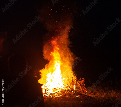 Beautiful big bonfire in the forest at night. A man looks at a bonfire, outdoor recreation, background, tourist