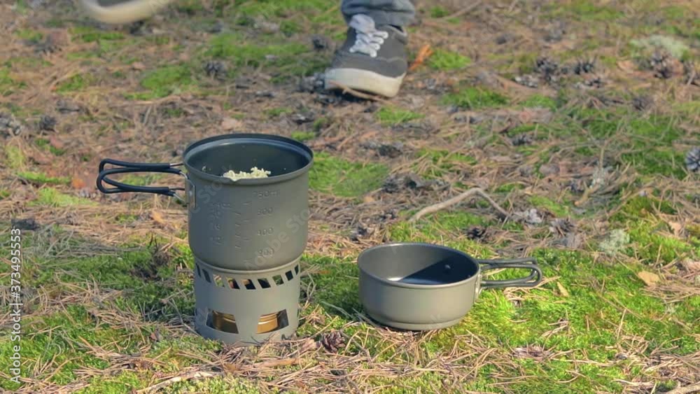 Man in a Forest is Cooking Pasta Using a Small Cook Set. Hiker in a Forest is Prepearing for the Lunch. Static Close-Up Shot Man in a Forest is Cooking Pasta Using a Small Cook Set. Hiker in a Forest is Prepearing for the Lunch. Static Close-Up Shot
