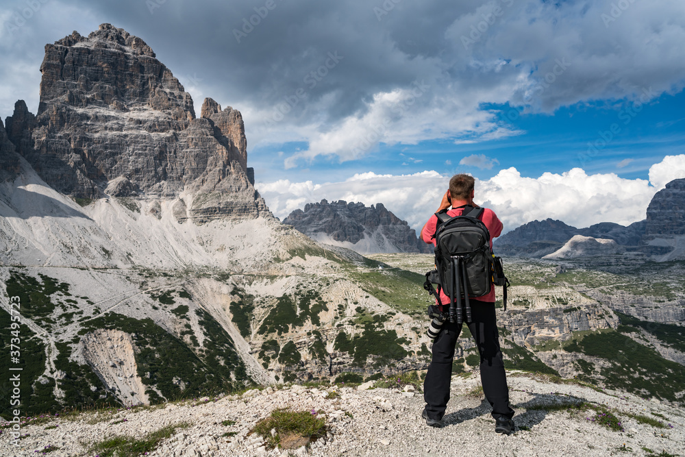 Nature photographer tourist with camera shoots while standing Italy Dolomites Alps.