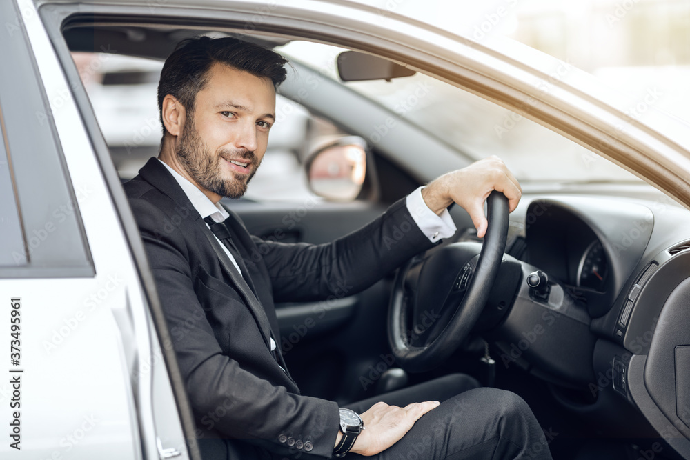 Happy young entrepreneur sitting in car, driving to office