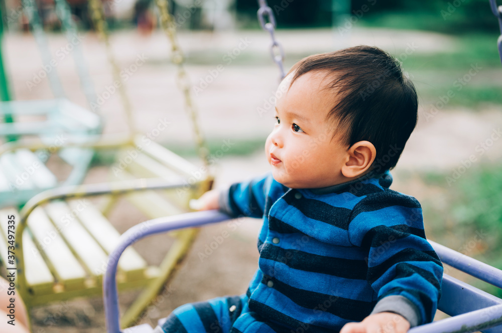 Little boy, kid having fun on swings at playground Little boy, kid having fun on swings at playground