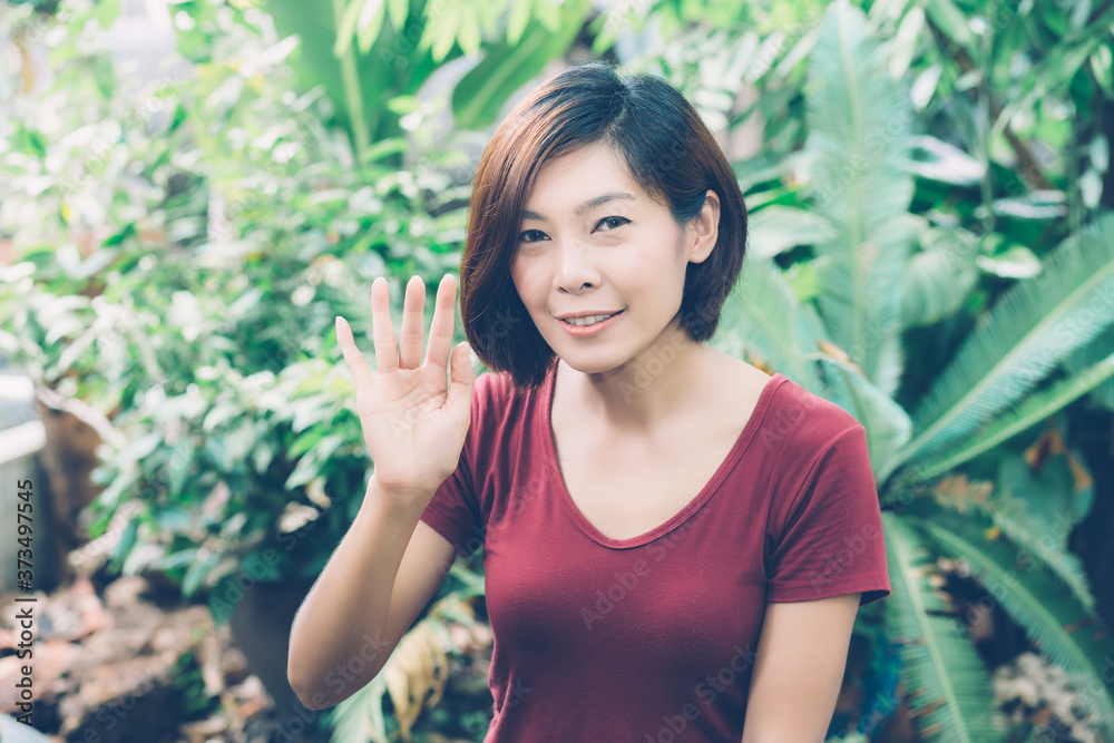 Beautiful portrait young asian woman smiling waving hand in garden at home, Friendly girl and expression positive of emotion, hello and greeting, one person, happy female excited and cheerful. Beautiful portrait young asian woman smiling waving hand in garden at home, Friendly girl and expression positive of emotion, hello and greeting, one person, happy female excited and cheerful.