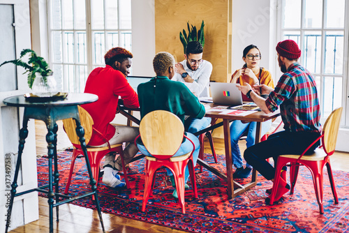 Group of diverse male and female students research education information during cooperation in trendy loft interior, youthful coworkers discussing developing project during association brainstorming