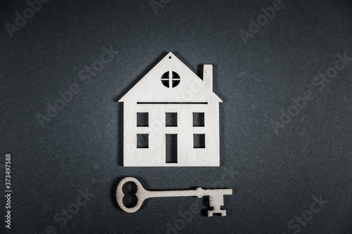 Real estate concept. Small toy wooden house with keys on grey background