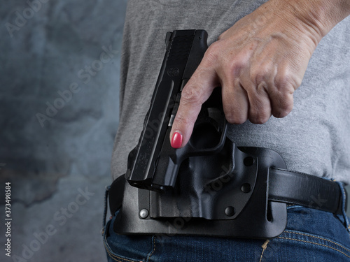 Women's hand holstering a gun close up