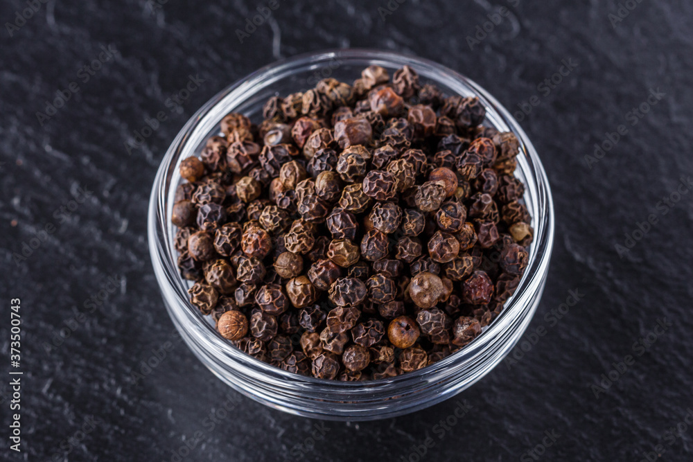 aromatic black pepper on a dark stone background aromatic black pepper on a dark stone background