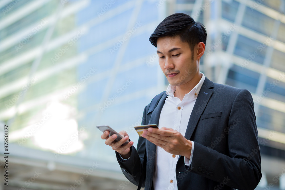 A young confident businessman use credit card to purchase some items by smartphone in the city. A young confident businessman use credit card to purchase some items by smartphone in the city.