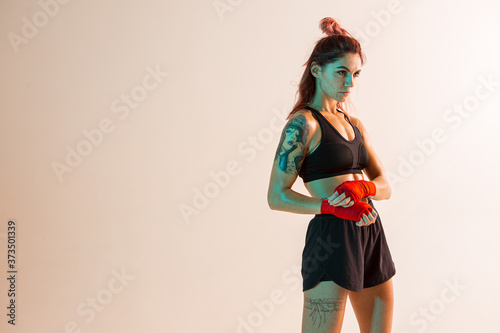 Athletic girl in stylish black sportswear stands in studio isolated on beige background. Women's active lifestyle