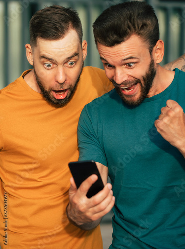 Photos Two happy excited fan friends in euphoria mood after winning in a bet with a sma