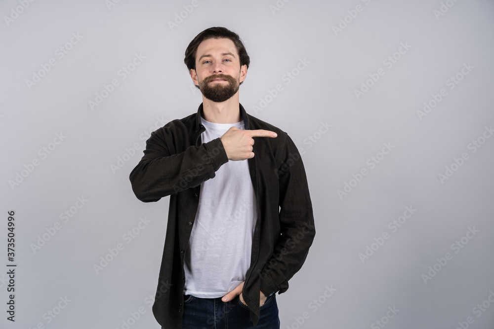 Young smiling man points with fingers in the right side isolated on white background.