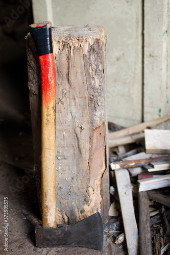Closeup vertical shot of an ax put by the stump